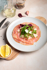 thinly sliced meat or fish fillet, with arugula, parmesan. Close-up, vertical frame