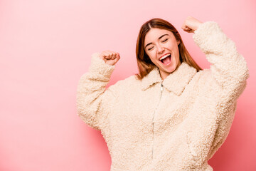 Young caucasian woman isolated on pink background raising fist after a victory, winner concept.