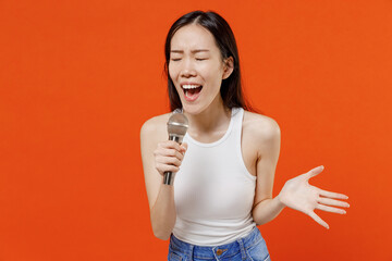 Excited jubilant exultant young woman of Asian ethnicity 20s years old in white tank top sing song...