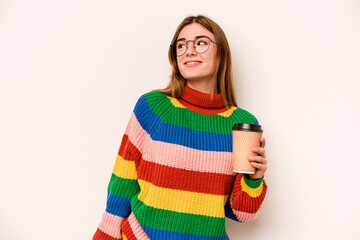 Young caucasian woman holding a take away coffee isolated on white background dreaming of achieving goals and purposes