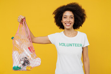 Young woman of African American ethnicity in white volunteer t-shirt hold plastic bag with trash...