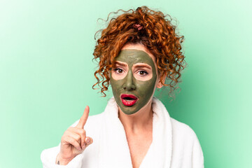 Young red hair woman with a facial aloe vera mask after a bath isolated having an idea, inspiration concept.