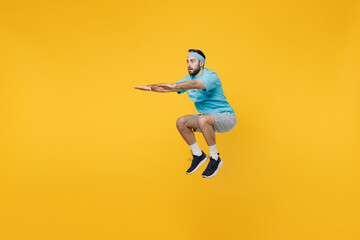 Fototapeta na wymiar Full body young fitness trainer instructor sporty man sportsman wear headband blue t-shirt spend weekend in home gym jump high isolated on plain yellow background. Workout sport motivation concept.