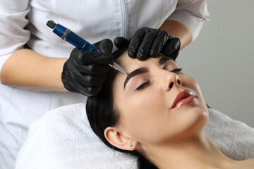 Young woman undergoing procedure of permanent eyebrow makeup in salon, closeup - obrazy, fototapety, plakaty