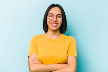 Fototapeta premium Young hispanic woman isolated on blue background who feels confident, crossing arms with determination.