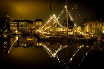 Port w nocy w mieście Gouda (Nederland). Oświecone lamkami stare mieszkalne statki.