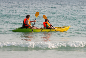 father and son enjoy paddling with the canoe at the sea