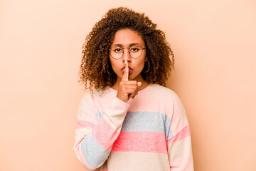 Young African American woman isolated on beige background keeping a secret or asking for silence.