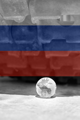 Naklejka premium The glass globe of planet Earth under the tracks of the tank in the colors of the flag of Russia.