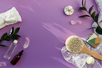 SPA beauty treatment: hygiene accessories, natural soap, essence oil and gel mock up, massage brush, bath bomb, sponges on purple background. Shadows, copy space