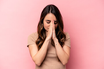Young caucasian woman isolated on pink background praying, showing devotion, religious person...