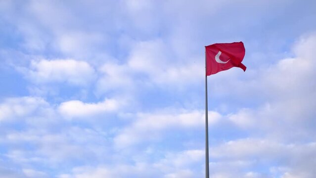 Turkish flag waving in blue sky with clouds , Republic Square in Antalya. A lively town square with equestrian statue of former President Ataturk surrounded by numerous cafes.