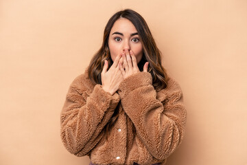 Young caucasian woman isolated on beige background shocked, covering mouth with hands, anxious to discover something new.