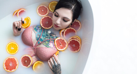 a naked girl with tattoos takes a vitamin bath with sliced oranges and grapefruits