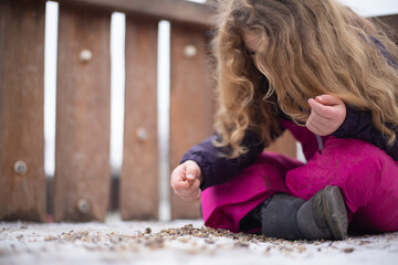 Mädchen spielt auf einem Spielplatz gedankenverloren mit steinen auf dem Boden