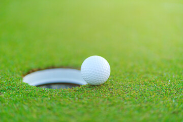 Golf ball on lip of cup at golf court