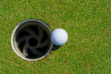 Golf ball on lip of cup at golf court