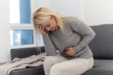 Young woman sitting on the bed with pain