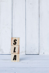 sla concept written on wooden cubes or blocks, on white wooden background.