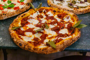 Pizza napoletana con sugo di pomodoro, mozzarella di bufala, salsiccia, carne e basilico fresco