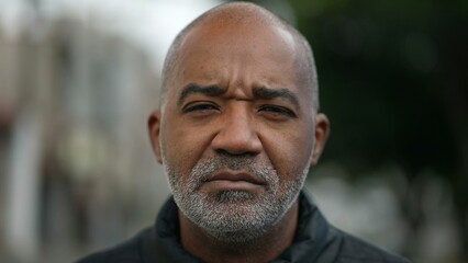 Portrait of a serious senior black man standing outside in street looking at camera