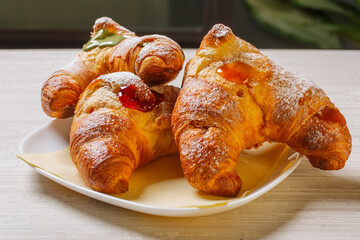 Tre cornetti caldi serviti in un bar come colazione ripieni di marmellata all'albicocca, marmellata ai frutti di bosco e crema al pistacchio
