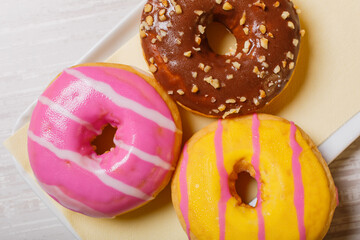 Tris di ciambelle cotte al forno e guarnite con glassa al cioccolato, glassa alla fragola e glassa al limone servite in un bar come colazione