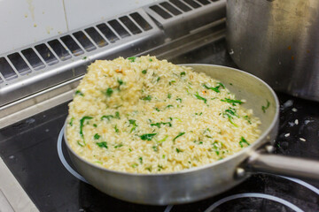 Risotto con rucola e vodka mentre viene saltato in una padella di una cucina professionale di un ristorante 