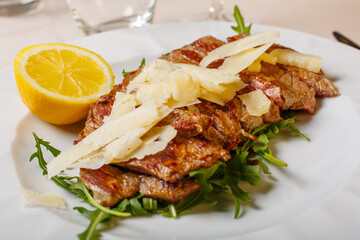 Tagliata di manzo cotta al sangue e servita in un ristorante elegante con scaglie di parmigiano e...