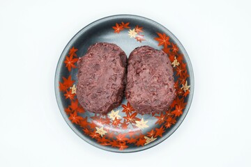 もみじ柄のお皿に乗った美味しそううな２つのおはぎ