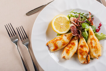 Antipasto di pesce con calamari cotti alla piastra e conditi con limone servito in un ristorante elegante