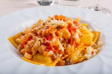 Piatto di ravioli conditi con sugo di pesce e pomodori e ripieni di pesce serviti in un ristorante elegante