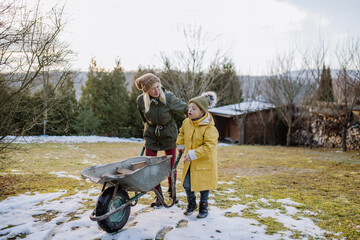 Boy with Down syndrome working in garden in winter with his grandmother.