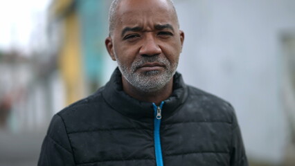 A serious black older man portrait face looking at camera tracking shot