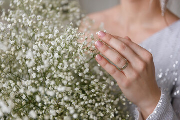beautiful woman, bride, touches with her hand a wedding bouquet of white gypsophila flowers....