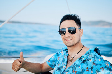 portrait of a happy brunette man in sunglasses on a speedboat laughing