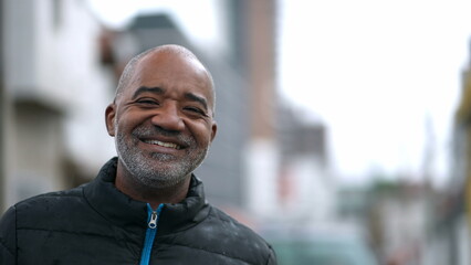 A happy senior black man portrait face smiling at camera standing outside in street