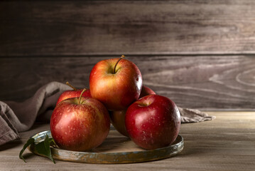 Fresh apples on a plate on a wood background.