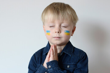 A Ukrainian boy on his face with the flag of Ukraine. World support in the war. No war. Hope for the world. Anxiety and anticipation. Children's tears. Save Ukraine