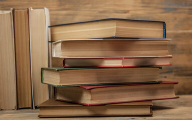 Stack of books on wooden table over rustic background with copy space