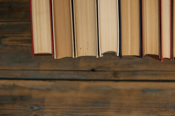 Stack of books on wooden table over rustic background with copy space