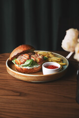Falafel burger with lettuce, tomato, onion, french fries, spicy fragrant sauce on a wooden table. Vegetarian food tasty and nutritious