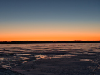 lake in ice in spring against the backdrop of a red sunset