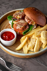 Falafel burger with lettuce, tomato, onion, french fries, spicy fragrant sauce on table. Vegetarian food tasty and nutritious