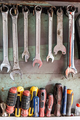 Candid collection of used screwdrivers hanging on a mechanic's garage handmade drawer shelf.