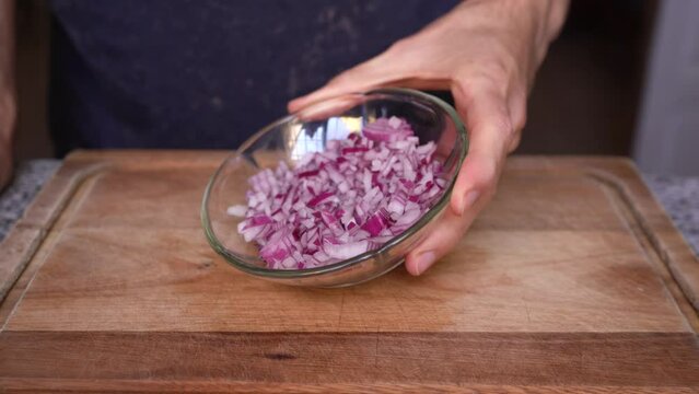 Cook showing purple onion cut in dices (brunoise cut)