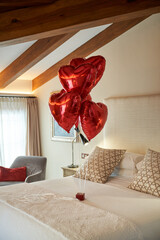 Hotel bedroom with red heart balloons prepared for loving couple