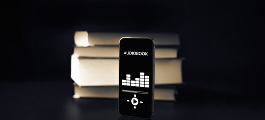 Audiobooks concept. Smartphone screen with audiobook application on paper books black background. Concept of education, library, students.