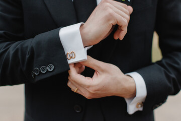 A man in a black suit straightens his sleeves A man buttoning a white jacket Groom getting ready in...