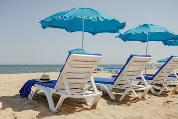sun loungers on the sand near the sea and umbrellas